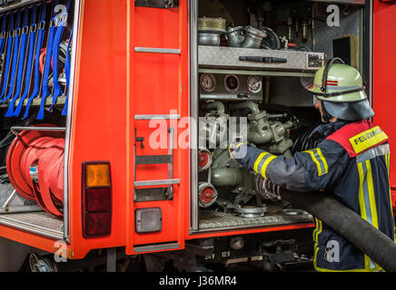 Firefighter in action with a fire hose on the fire truck - HDR Stock Photo