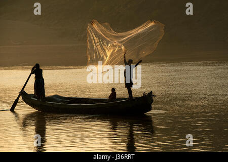 Fisherman standing on platform of Chinese net observing calm water