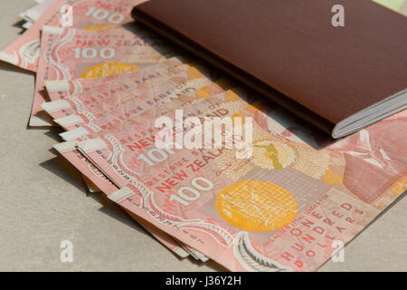stack of new zealand 100 dollars bank note and red cover personal passport book on cement floor Stock Photo