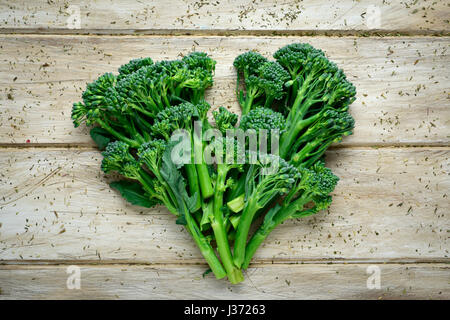 high-angle shot of some stems of broccolini forming a heart on a wooden rustic table Stock Photo