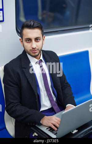 Middle-Eastern Businessman Using Laptop in Subway Stock Photo