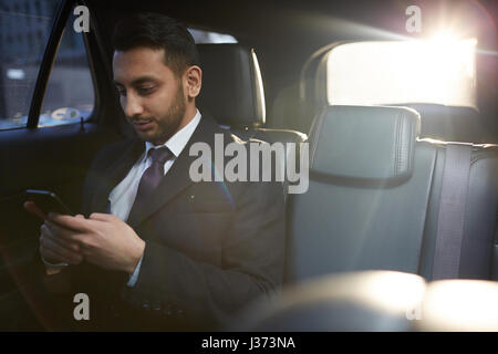 Businessman Browsing Internet in Luxury Car Stock Photo