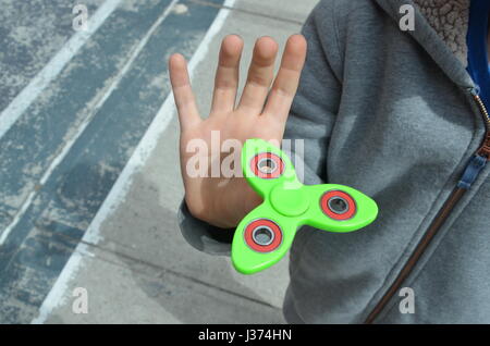 A boy playing with a green fidget spinner in brooklyn new york USA Stock Photo