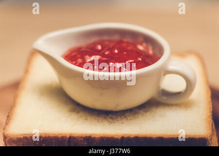 Toast with strawberry jam on a plate on table. Stock Photo