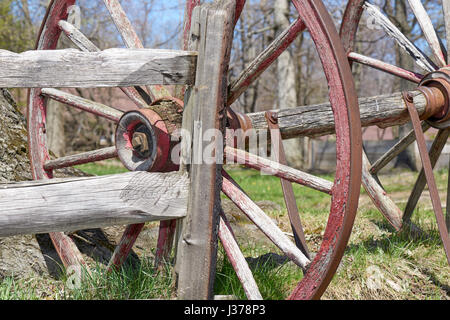 conestoga wagon wheel resting against split-rail fence in barnyard Stock Photo