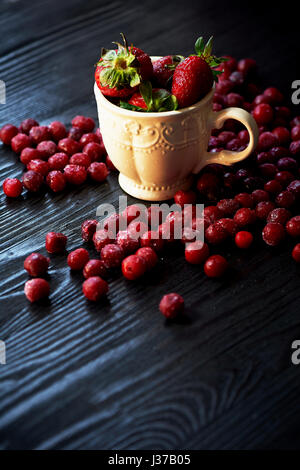 Bowl of juicy strawberries on a dark wood background. On top of Rossana berry. Cherry, strawberry, cranberry Stock Photo