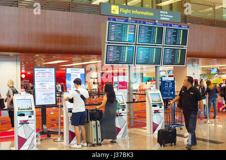 SINGAPORE - JANUARY 13, 2017: Passengers at self check-in kiosk near information board in Changi Airport. Changi Airport serves more than 100 airlines Stock Photo