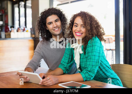 Portrait of young man and woman using digital tablet in restaurant