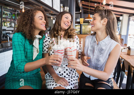 Happy female friends cheering drink in restaurant