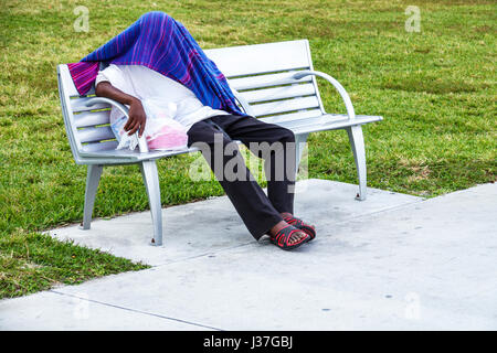 Miami Beach Florida,Lummus Park,park bench,Black man men male,sleeping,covered face,head,blanket,hiding,mental health illness,homeless,teen teens teen Stock Photo