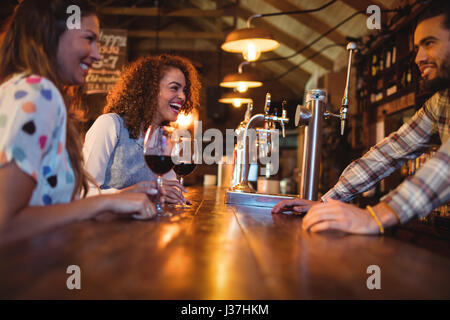 Young women interacting with bartender at counter in pub Stock Photo
