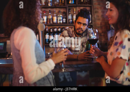 Young women interacting with bartender at counter in pub Stock Photo