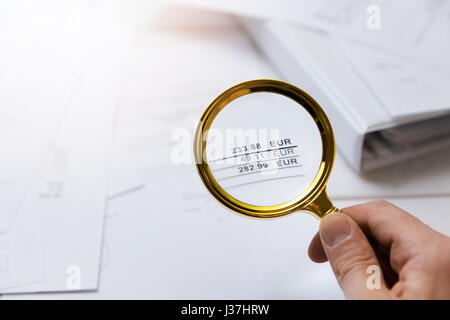 audit concept - auditor checking bills with magnifying glass Stock Photo