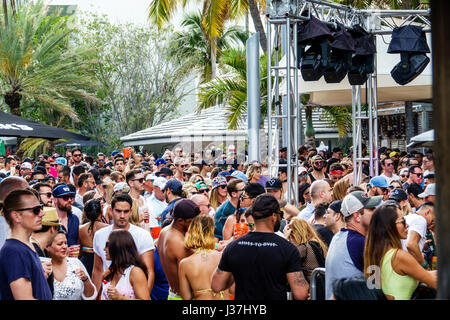 Miami Beach Florida,Miami Music Week,hotel pool party,crowd,standing,dancing,drink drinks drinking,young adult,men,women,stage,lighting,truss,FL170326 Stock Photo