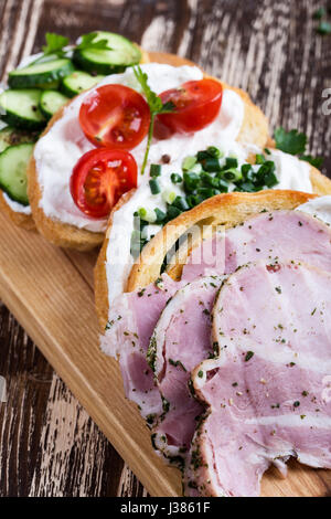 Assorted sandwiches  with cream cheese, ham,cucumbers, tomatoes and green onion, selective focus Stock Photo