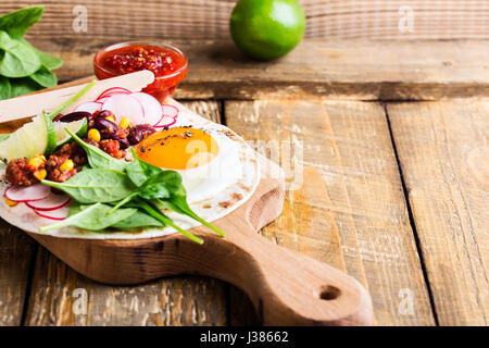 Fried egg tacos with chili con carne on rustic cutting board, Mexican traditional food Stock Photo