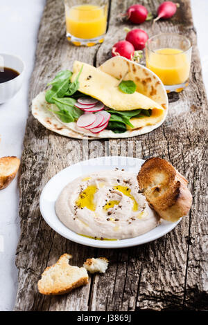 Brunch table. White bean dip on plate, and homemade omelette spinach tacos on rustic wooden table Stock Photo