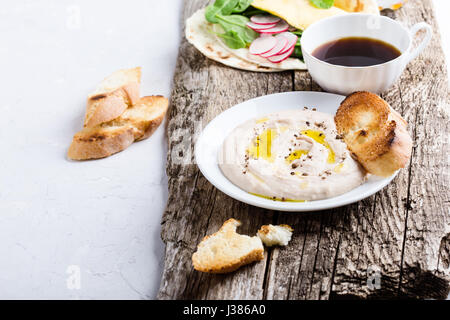 Brunch table. White bean dip on plate, and homemade omelette spinach tacos on rustic wooden table Stock Photo