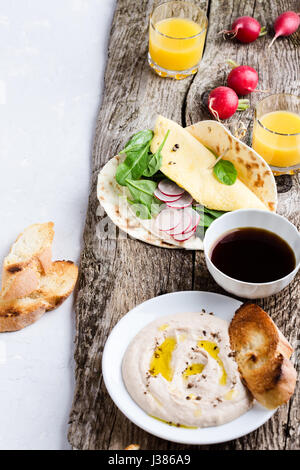 Brunch table. White bean dip on plate, and homemade omelette spinach tacos on rustic wooden table Stock Photo