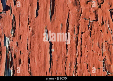 Close up of old wooden board with cracking red paint for background or texture.
