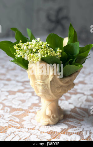 Beautiful bouquet of lily of valleys in an elegant vase isolated on a white tablecloth Stock Photo