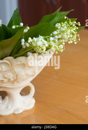 Beautiful bouquet of lily of valleys in an elegant vase isolated on the wooden background Stock Photo