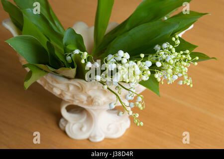 Beautiful bouquet of lily of valleys in an elegant vase isolated on the wooden background Stock Photo