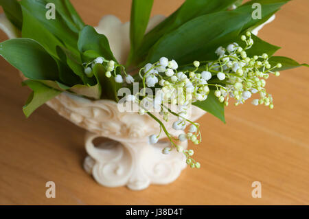 Beautiful bouquet of lily of valleys in an elegant vase isolated on the wooden background Stock Photo