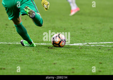 soccer player's close up legs, kicking the ball on the pitch grass. Stock Photo