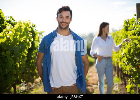 Smiling young man standing at vineyard during sunny day Stock Photo
