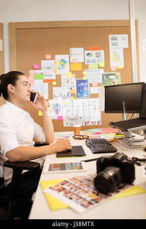 Side view of designer talking on phone while working in creative office Stock Photo
