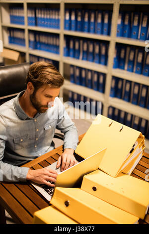 High angle view of businessman using laptop by files on table in storage room Stock Photo