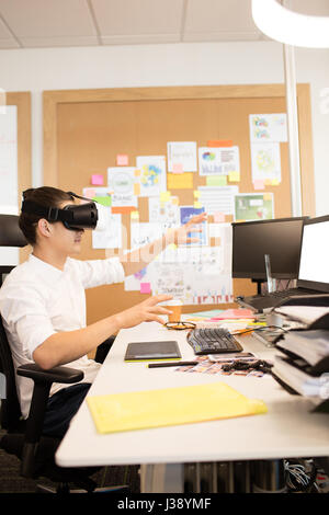 Creative designer gesturing while experiencing vr glasses Stock Photo