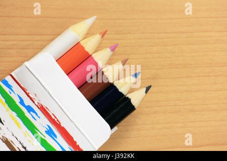 Colorful pencils in paper box on wood Stock Photo