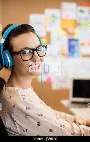 Portrait of smiling designer wearing blue headphones in office Stock Photo