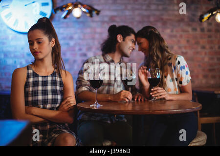 Jealous woman ignoring affectionate couple in pub Stock Photo