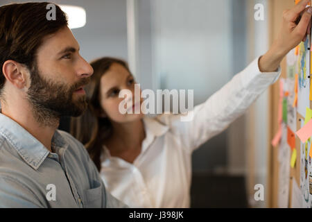 Serious businessman analyzing charts with female colleague at office Stock Photo