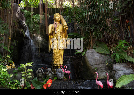 Golden Buddha statue and small artificial waterfall at the Golden Mount at Wat Saket in Bangkok, Thailand. Stock Photo