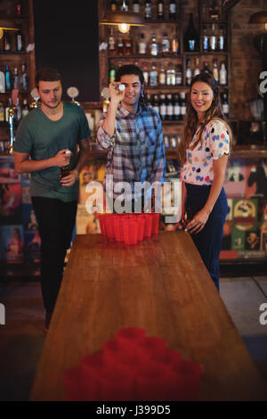 Group of happy friends playing beer pong game in pub Stock Photo