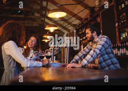 Young women interacting with each other at counter in pub Stock Photo