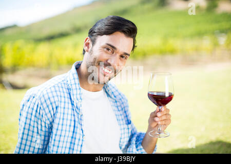 Portrait of smiling man holding red wine at vineyard Stock Photo