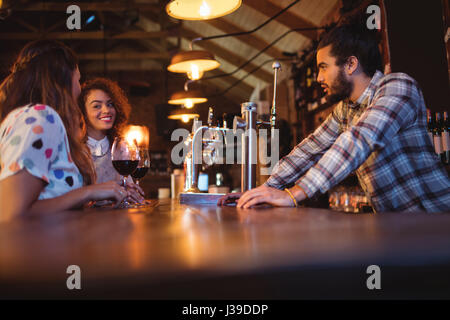 Young women interacting with each other at counter in pub Stock Photo