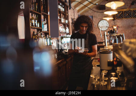 Young waiter writing on diary in pub Stock Photo