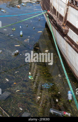 Concept of polution : Fishing boats on the dirty beach full of plastic trashes Stock Photo