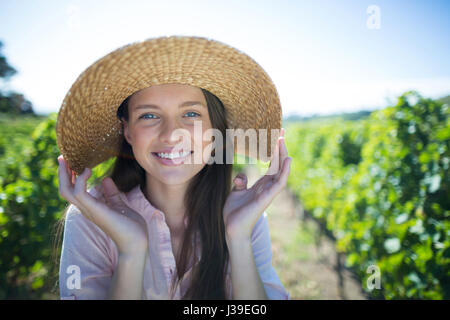 Close up portrait of beautiful young woman wearing hat on sunny day at vineyard Stock Photo