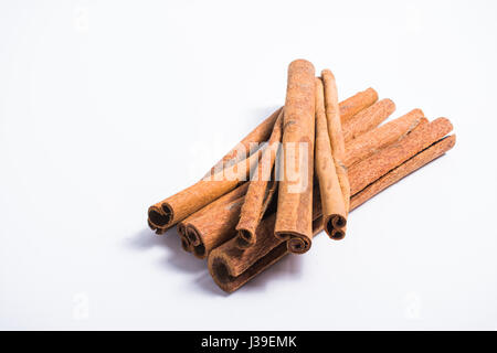 Pile of cinnamon sticks stacked on top of each other against white background Stock Photo