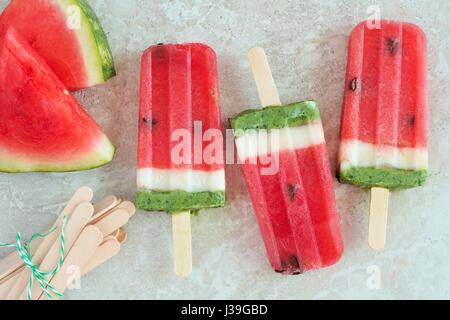 Watermelon popsicles with fresh melon slices on a white marble background Stock Photo