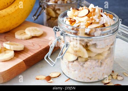 Healthy overnight oats with bananas and nuts in glass canning jars Stock Photo