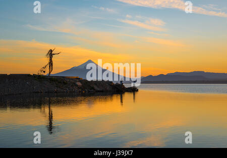 Two local fisherman at the Llanquihue lake at sunrise seen from Puerto Varas with the Osorno volcano, near Puerto Montt in the Lake District of Chile. Stock Photo