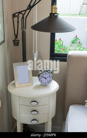 black lamp, picture frame and alarm clock on bedside table Stock Photo